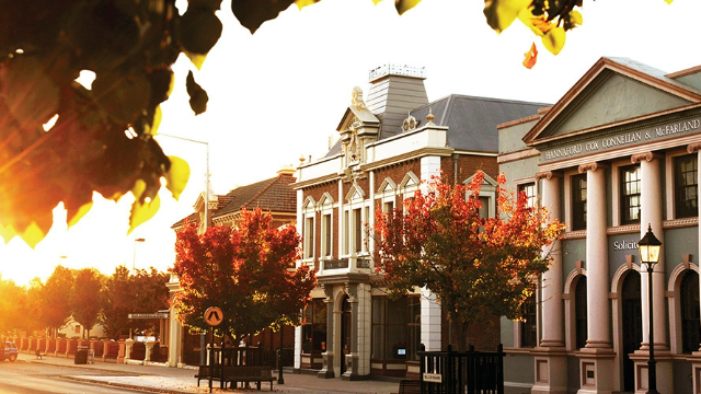historic-street-in-orange-nsw-640x360 Historic Victorian and colonial style buildings along a street, lit by a flash of orange sunset through tree leaves.