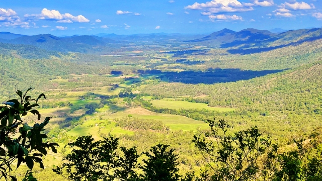Issac region QLD landscape valley daytime view down into valley with paddocks and tree-covered slopes on a sunny day