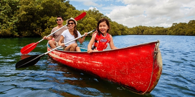 man, woman and child paddling a red kayak