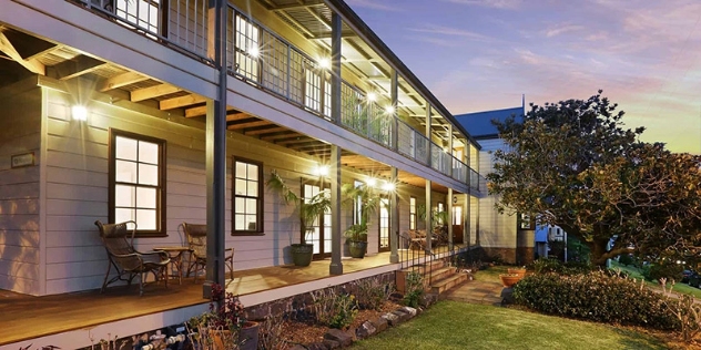 pretty two-storey weatherboard property with upper deck at dusk