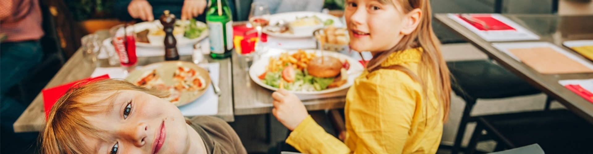 Kids eating a meal family enjoying a meal together with focus on two young children who are looking at the camera