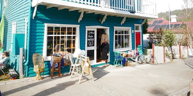 pretty turquoise weatherboard shop building with white framed windows and vintage cane furniture out the front