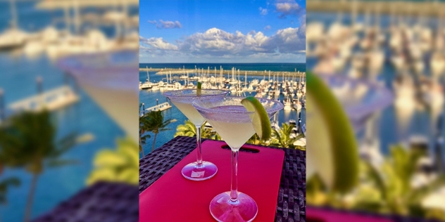 two margarita cocktails with a view of a marina in the background on a sunny day