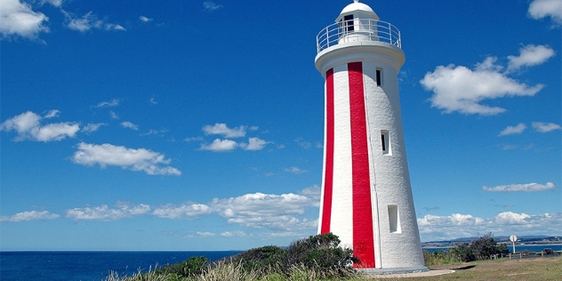 lighthouse painted white with two bold, vertical red stripes