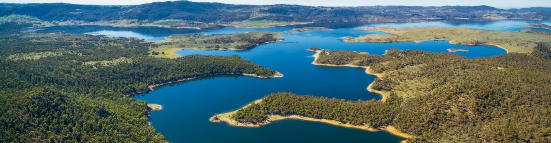 myall-lakes-panorama-nsw-1920x500 A weaving inlet of dark blue lakes through heavily forested shores, with tall hills on the horizon.