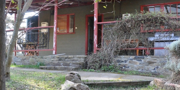 front veranda and door of 1920s farmhouse with weathered red posts