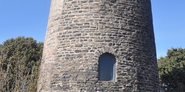 central section of pale grey brick tower with a small arched window