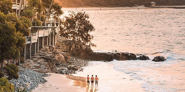 three people standing on the shore