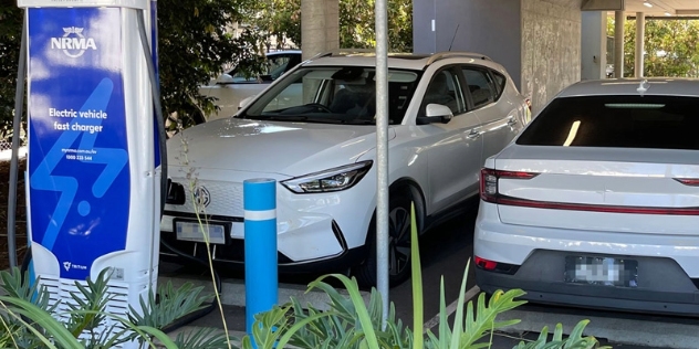 electric vehicle plugged into an NRMA fast charger in a car park under the Grafton Library