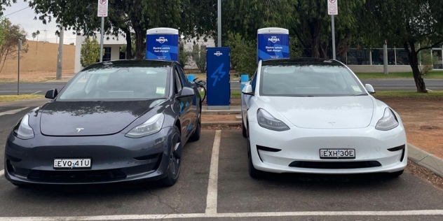 black and white teslas sit charging side-by-side at the NRMA charging station