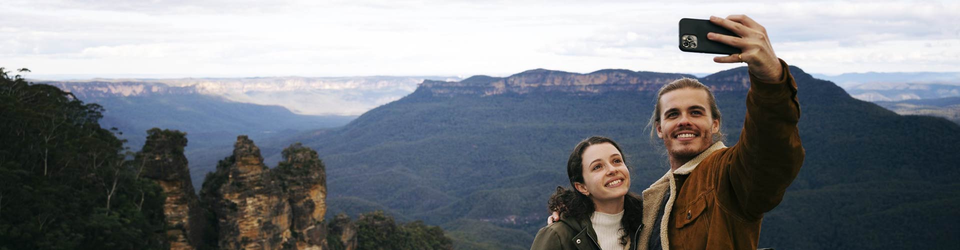 A couple takes a selfie in front of a scenic Blue Mountains view