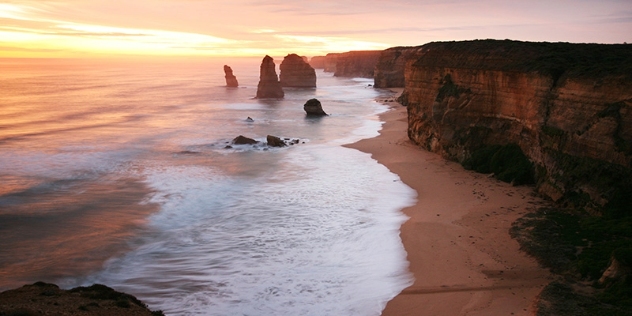 view of the 12 apostles rock formations with the rocky coastline in the background at sunset