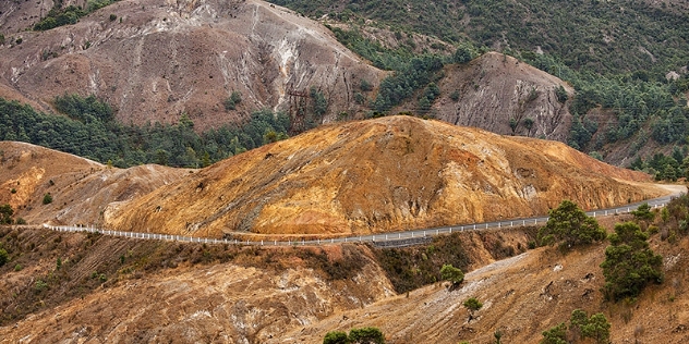 fenced road winds around bare, rocky landscape