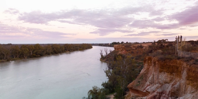 wide still river flanked by sandstone rocks and gum trees