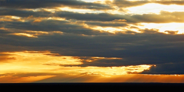 orange sunset through clouds over the darkened mundi mundi plains