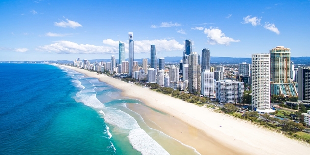 arial view of city skyscrapers next to white sandy beaches, looking out to the ocean