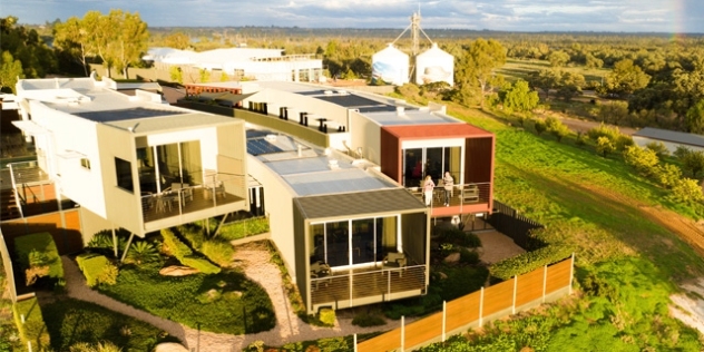 three modern rectangular buildings on stilts facing the Murray River