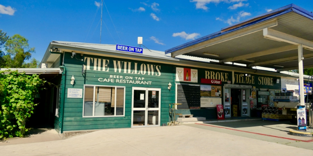 A green shop with the The Willows in white script across the front, attached to a petrol station and general store.