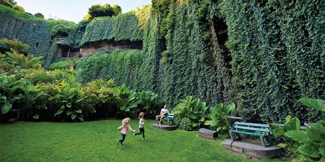 children play on the lawn in the sunken garden, flanked by tall hedges