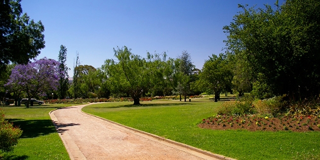 wide gravel path through grassy area with flower beds