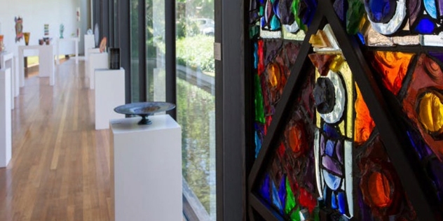 view through the stained-glass open door to a roof with rows of white square pedestals displaying sculptures