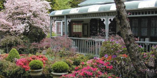 a historic verandah surrounded by a colourful garden