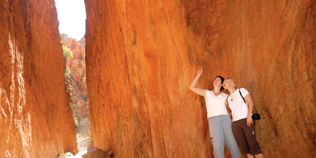 two people looking up at the orange rockface