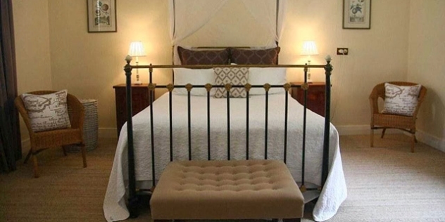 antique wrought iron bed with white coverlet in a stylish room decorated in shades of cream and beige