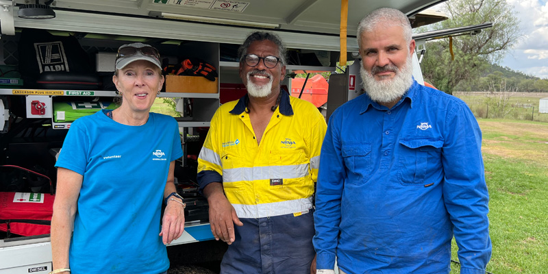 three nrma volunteers smiling in front of a vehicle