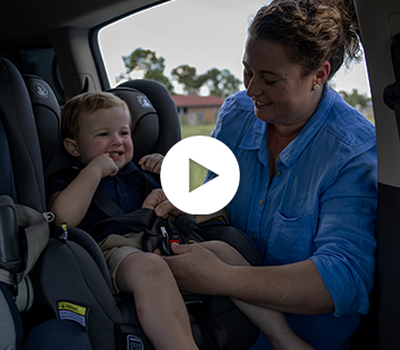 Mother securing child in car seat